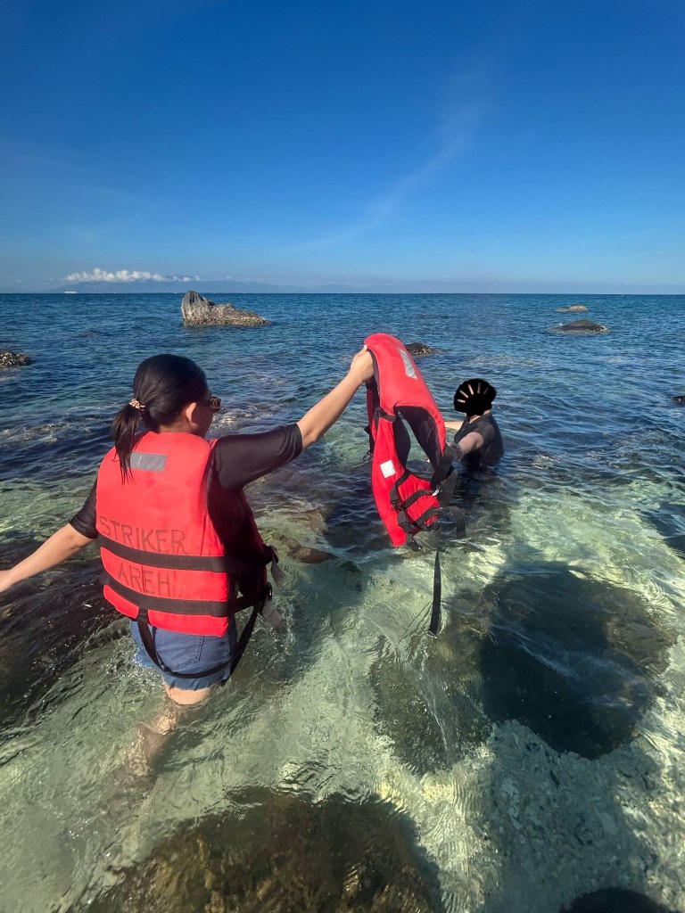 Tourists wearing life vests at a rocky beach in Tingloy, Batangas.
